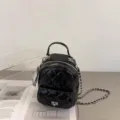 Black quilted leather mini backpack detail showing chain strap and twist lock design. - Black