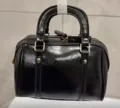 Detailed view of black patent leather Boston handbag, classic style with double handles. - Black