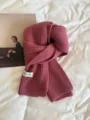 Close-up view of cozy knit scarf texture, soft winter accessory detail shot on bed. - Raspberry Pink