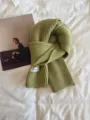 Green knitted scarf detail showcasing soft wool texture and minimalist winter warmth. - Mustard Green