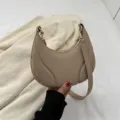 Bolso de hombro minimalista de cuero suave en color beige con diseño curvo elegante. - Caqui