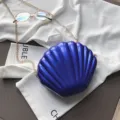 Borsa a tracolla da donna in pelle verniciata blu a conchiglia con catena dorata chic. - Blu