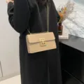 Bolso bandolera elegante para mujer en charol beige con cadena dorada y cierre metálico de moda. - Caqui