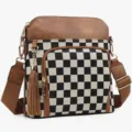 Detailed view of the black and white checkerboard crossbody bag with brown leather trim and tassel. - Brown