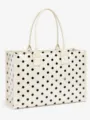 Polka dot tote bag detail view, showing shiny clear surface, black dot pattern and sturdy handles. - White
