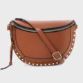 Detail view of brown leather crescent crossbody bag with gold tone studs and adjustable strap. - Brown