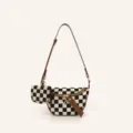 Detailed view of black and white checkered canvas crossbody bag with brown leather strap. - Brown