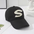 Classic black cotton baseball cap featuring a stylish beige letter S embroidered patch. - Black