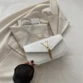 Bolso bandolera minimalista blanco con logo V dorado y correa de cadena elegante para diario - Blanco