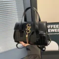 Zwarte handtas van PU-leer met krokodillenprint, gouden kwastje en handige schouderriem. - Zwart