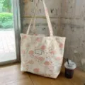 Vue détaillée du sac cabas jacquard floral rose vintage avec des détails dorés sur table. - Encolure asymétrique une épaule
