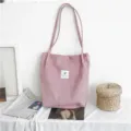 Gros plan d'un sac cabas d'épaule en velours côtelé rose montrant la texture et le design. - Rose racine de lotus