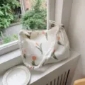 Vue détaillée du sac cabas en tissu plissé blanc avec de jolies tulipes orange. - Bretelles plissées