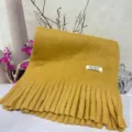 Close-up detail of the soft yellow plush scarf with fringe, showing texture and sewn brand label. - Ginger Yellow Soft Plush Scarf
