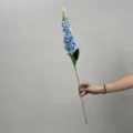 Gros plan détaillé de la tige de fleur artificielle bleue, avec des pétales et des feuilles vertes. - Bleu Clair