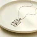 Silver geometric swirl pendant necklace close-up, trendy titanium steel minimalist jewelry. - Necklace