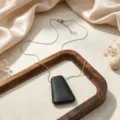 Minimalist geometric pendant necklace detail, sleek metal chain with modern dark charm. - Necklace