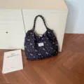 Detail shot of black floral quilted tote bag with rope handles and woven label. - Black