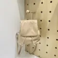 Beige minimalist backpack detail showcasing front flap closure and drawstring design. - Apricot