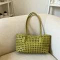 Detailed close up view of the green woven leather handbag texture and scalloped edge design. - Green