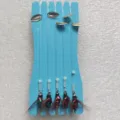 Detalle de primer plano de señuelos de pesca con cucharas metálicas en tablero de espuma. - Montaje Mixto de 3 Colores