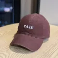 Detail shot of the dark maroon baseball cap featuring white CARE letter embroidery. - Adult 54-60 Adjustable / Burgundy