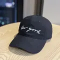 Detailed close-up of a black baseball cap featuring white New york cursive embroidery. - Adult 54-60 Adjustable / Black