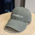 Close-up of stylish washed baseball cap with embroidered logo detail on wooden table surface. - Adult 54-60 Adjustable / Olive