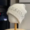 Detailed view of women's cozy knitted beanie hat adorned with sparkling rhinestones and pearls. - Adult One Size (54-60cm) / Beige