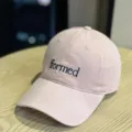 Close-up detail of the pink cotton baseball cap featuring stylish front black embroidery text. - Pink