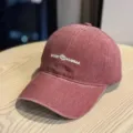 Close-up of vintage washed baseball cap with white embroidered text detail and curved brim. - Adult 54-60 Adjustable / Burgundy