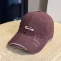 Close-up of distressed maroon baseball cap with white cursive embroidery, soft crown design. - Adult 54-60 Adjustable / Burgundy