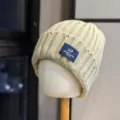 Close-up detail of the cozy knitted winter beanie with cute sheep logo patch and warm knit. - Adult One Size (54-60cm) / Khaki