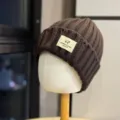Detailed view of the dark brown knit beanie featuring a cute sheep patch and cozy texture. - Adult One Size (54-60cm) / Coffee