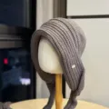 Detailansicht der graubraunen Strickmütze mit Ohrenklappen, weiche Textur und kleines Schild. - Erwachsene 54-60 Einheitsgröße / Hellbraun