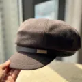 Detailed view of the brown woolen newsboy cap featuring a stylish leather strap and metallic accent. - Adult 54-60 Adjustable / Coffee