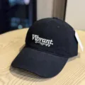 Close-up detail of a black baseball cap with white embroidered text on the front crown. - Adult 54-60 Adjustable / Black