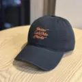 Schwarze Baseballkappe Detailansicht mit orangefarbenem gesticktem Text und breiter Krempe. - Erwachsene 54-60 Einstellbar / Schwarz