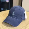 Detail view of a dark blue washed cotton baseball cap featuring white B NECESSITY embroidery. - Adult 54-60 Adjustable / Navy Blue