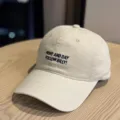 Detailed view of the beige washed cotton baseball cap featuring front slogan embroidery. - Adult 54-60 Adjustable / Beige