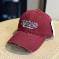 Detailed close-up of a stylish distressed red baseball cap featuring front embroidery. - Adult 54-60 Adjustable / Burgundy