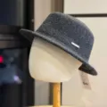 Detail view of a stylish dark grey wool bucket hat with a metal logo tag for autumn. - Adult 54-60 Adjustable / Black
