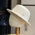 Detailed view of the elegant wool bucket hat, featuring a stylish metal logo and soft fabric. - Adult 54-60 Adjustable / Beige