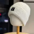 Beige knit beanie detail view, warm winter hat with metal number 7 patch and pearl trim. - Adult One Size (54-60cm) / Beige