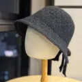 Detailed view of dark grey knitted bucket hat with cute bow knot, showing soft warm woolen texture. - Black