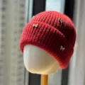 Close-up detail of the red knitted winter beanie featuring elegant metallic bow accents. - Adult One Size (54-60cm) / Burgundy