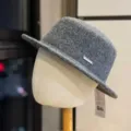Close-up detail of the elegant grey wool fedora hat with metallic brand badge and tag. - Adult 54-60 Adjustable / Dark Gray