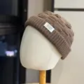 Gedetailleerde close-up van een bruine gebreide muts met textuur en voorste label. - Volwassen 54-60 Verstelbaar / koffiekleur