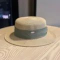 Close-up detail of the stylish straw boater hat featuring a green ribbon and metal tag. - Adult Adjustable 54-60 / Khaki Green Ribbon