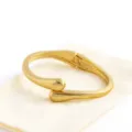 Close up of minimalist gold metal drop cuff bracelet showcasing polished smooth geometric detail. - Style Four / Gold